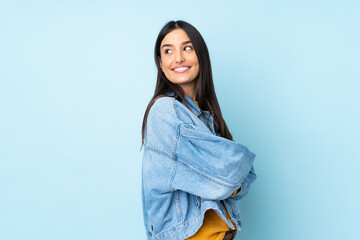 young caucasian woman isolated on blue background looking to the side and smiling