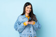 © luismolinero - Young caucasian woman isolated on blue background sending a message with the mobile