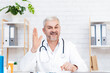 © Prostock-studio - Doctor in white medical uniform with stethoscope sit at desk look at camera in hospital