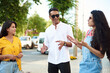© etonastenka - Young people having fun outdoors. A group of multi-ethnic friends are talking and laughing while standing in the street