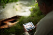 © Martin Barraud/Caia Image - Man video chatting with digital tablet from riverbank