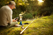 © Martin Barraud/Caia Image - Man with smart phone taking a break from fishing making coffee
