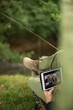 © Martin Barraud/Caia Image - Man fishing and video chatting with digital tablet at riverbank