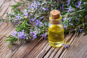 Wall Mural - Rosemary oil. Rosemary essential oil jar glass bottle and branches of plant rosemary with flowers on rustic background.