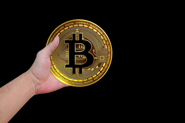 Hand holding Bitcoin isolated on black background. Cryptocurrency symbol, close up.