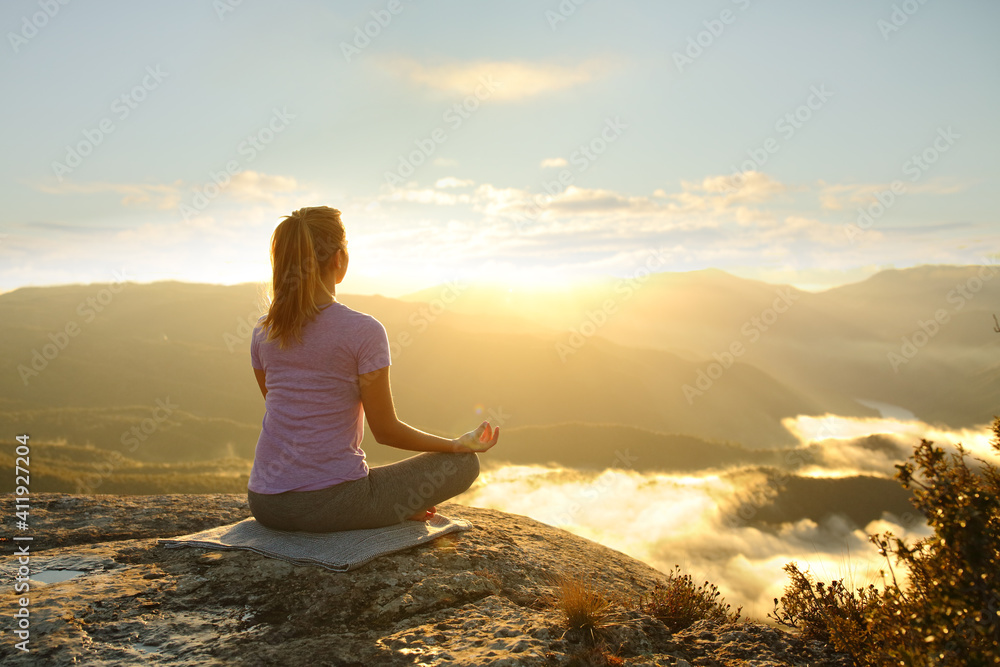 Woman meditating practicing yoga in the mountain - obrazy, fototapety, plakaty 