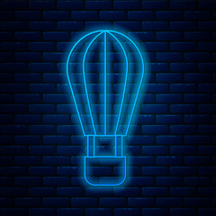 Sticker - Glowing neon line Hot air balloon icon isolated on brick wall background. Air transport for travel. Vector.