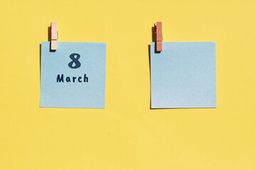 March 8st. Day of 8 month, calendar date. Two blue sheets for writing on a yellow background. Top view, copy space. Spring month, day of the year concept