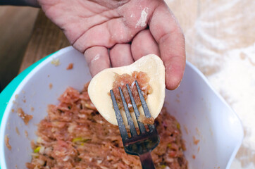 A girl puts meat in dumplings dough