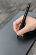 A girl draws a picture with a graphics tablet. Close-up