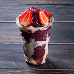 brazilian frozen açaí in a plastic cup with condensed milk and strawberry. fruit from the amazon.