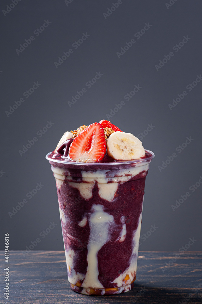 Brazilian frozen açaí in a plastic cup with condensed milk, banana