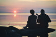 Guy and  girl in love are sitting on the shore of the lake at sunset and sing a song under the ukulele.