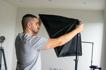 Photo of a young and attractive photographer preparing the photography set of lights 