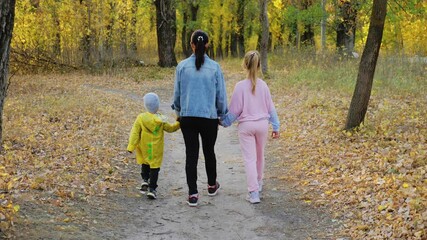 beautiful young woman with two children walking in forest.
