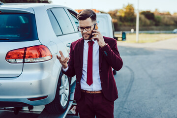 Wall Mural - Elegant middle age business man calling towing service for help on the road. Roadside assistance concept.