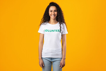 Wall Mural - Smiling Volunteer Woman Wearing White T-Shirt Standing On Yellow Background