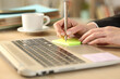 © PheelingsMedia - Teleworker writing sticky note on a laptop at homeoffice