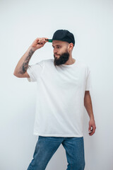 Wall Mural - Young bearded hipster guy wearing white oversized blank t-shirt on a white background. Mock-up for print. T-shirt design and advertising concept.