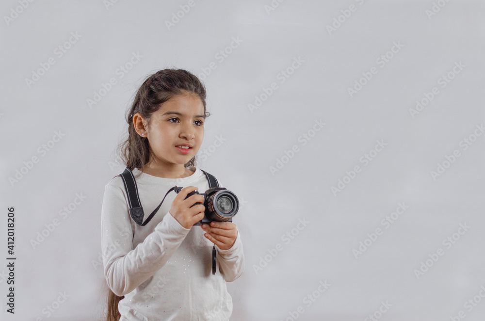Portrait of a little girl smiling and holding a camera while standing ...