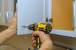 © ungvar - Assembling of install new handle on the white cabinet furniture
