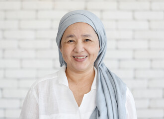 Portrait of an Asian woman with a clothe covered head and smile with happiness to the camera. Concept of a cancer patient with effected of chemo treatment but still feel hope and strength