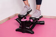 © JoseManuel - Close up young woman using stepper on a pink floor. Concept of training girl at home.