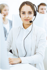 Wall Mural - Call center. Group of diverse operators at work. Beautiful woman in headset communicating with customers of telemarketing service. Business concept