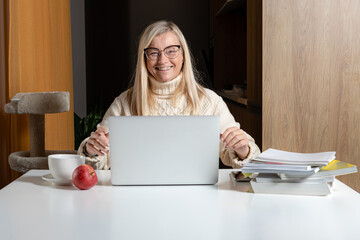 Wall Mural - middle aged businesswoman sitting at desk working with laptop from home office