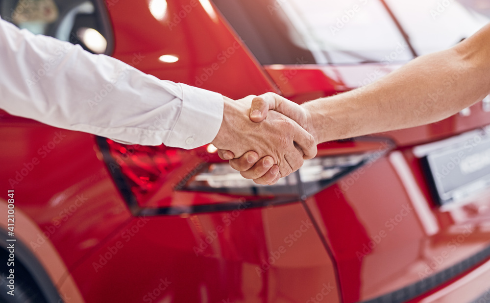 Crop client and car dealer shaking hands