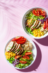 Poster - Grilled chicken breast with brown rice and vegetables in white plate, top view, pink background. Healthy food concept.