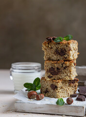 Wall Mural - Oatmeal squares with chocolate and a cup of milk, light concrete background. Diet bars. Healthy bakery for breakfast or dessert.