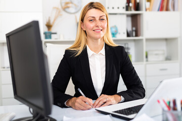 Wall Mural - Portrait of confident businesswoman in formal wear working on laptop in business office