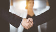 © cameravit - Unknown businesspeople are shaking their hands after signing a contract, while standing together in a sunny modern office, close-up. Business communication, handshake, and marketing concept