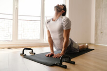 Focused Athletic Man Stretching His Body While Working Out At Home