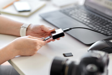 technology, post production and vlog concept - close up of woman with sd memory card reader working 