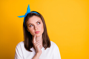 Sticker - Photo of minded young woman look empty space finger on chin isolated on bright yellow color background