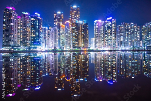 Illuminated Modern Buildings In City Reflecting In Water At Night