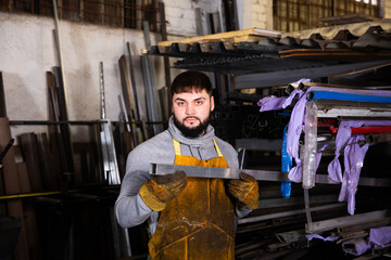 Portrait of man looking at profile steel tube. High quality photo