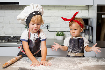 Brother and sister in the kitchen, with flour hands.