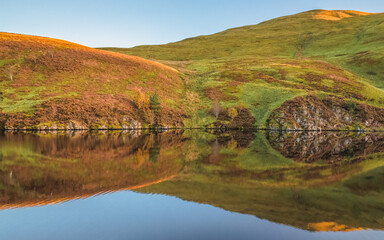 Wall Mural - A calm, still peaceful countryside landscape reflection at Glencorse Reservoir in the Pentland Hills Regional Park in Edinburgh, Midlothian, Scotland.