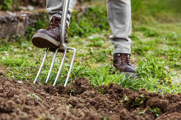 man is digging with a gardening fork in his garden