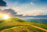 Fototapeta Fototapety góry  - mountain landscape on a bright spring sunset. path through meadow in grass on the hill in evening light. wonderful weather with fluffy clouds on the sky. borzhava ridge of carpathians