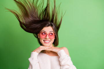 Poster - Photo of young attractive pretty happy smiling dreamy girl in funky glasses with flying hair isolated on green color background