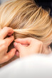 © okskukuruza - Closeup back view of a hairdresser stabs blonde hair with a hairpin for a young woman in a hair salon