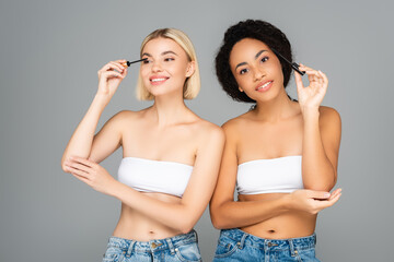 Wall Mural - Interracial women applying mascara isolated on grey