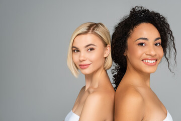 Wall Mural - Young multicultural women smiling at camera isolated on grey