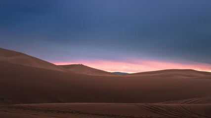 A moody sunrise or sunset landscape view of the desert sand dunes of Erg Chebbi near the village of Merzouga, Morocco.