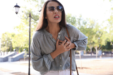 Canvas Print - Young woman having heart attack in park