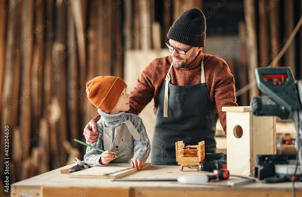 Father and son making bird house in workshop - obrazy, fototapety, plakaty 